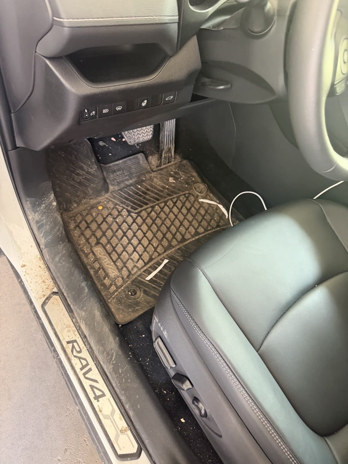 RAV4 driver footwell before detailing, with a mud-caked rubber mat and a gritty door sill
